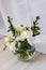 White freesia flowers in a spherical glass vase