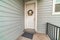White front door with floral wreath against gray wooden exterior wall siding