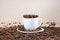 White full of roasted coffee beans cup standing on a white plate on tablemat.