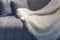 White fur fluffy plaid on a gray velor sofa. Coziness and comfort in interior decoration. Close-up. Space for text