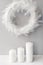 White fuzzy wreath made from feathers on a wall with three big candles. Interior decoration on minimal style.