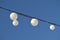 White garland balloons oscillate in the wind against blue sky and clouds, peaceful landscape