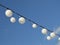 White garland balloons oscillate in the wind against blue sky and clouds, peaceful landscape