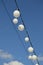 White garland balloons oscillate in the wind against blue sky and clouds, peaceful landscape, vertical, shot