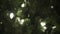 White garland lights on a Christmas tree under snowfall