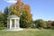 White gazebo and park benches in autumn