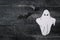 White ghost costume on dark black wooden background. Minimalistic Halloween scary concept. craft paper ghosts