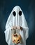 White ghost holding a pumpkin with candies.