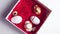 White gift box with red confetti decorated with golden eggs and quail eggs on a white table. Female hand takes eggs