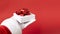 white gift box with red ribbon bow in santa hand on red background.