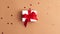 White gift box with a red satin ribbon bow tied on brown background with red stars shapes. Stop motion animation Christmas