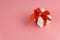 White gift box with red strap on colour background, engagement ring box