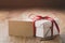 White gift box with thin red ribbon bow on old wood table with paper card