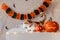 White ginger cat sits on table next to pumpkin lantern against the backdrop of Halloween decorations