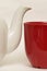 White glazed faience tea pot and red cup