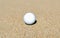 White golf ball isolated on a sand trap background, soft focus