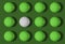 White golf ball and lots of green golf balls on a green background. The photo shows the message of `being your own` to succeed.