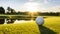 White golf ball on picturesque green golf course at the sunset. Pitch is perfectly prepared, grass is neatly trimmed.