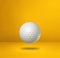 White golf ball on a yellow studio background