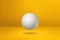 White golf ball on a yellow studio background