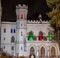White gothic castle with colored windows at night
