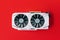 White graphics card with two black fans is located in the middle of red background. Trending computer peripherals