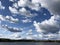 White and gray clouds on the blue sky above the big calm spring lake