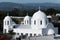 White Greek Orthodox Church with three crosses mountain hills in background