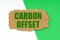On a white-green background lies a piece of cardboard with the inscription - Carbon offset