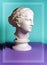 White gypsum copy of ancient statue Venus head on a green purple background. Plaster sculpture woman face.