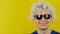 White hair curly smiling man with black sunglasses, funny and cheerfully human emotion, on yellow wall background