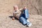 White-haired senior man  lying down on the rocks enjoying the sun in a winter day. Relaxed elderly in excursion outdoors