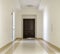 White hallway with marble floor and brown door