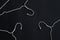 White hangers on black paper background. Minimalistic fashion concept.