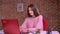 White happy business woman works on her laptop and typing while sitting at the table in pink sweater indoor