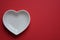 White heart shaped dish isolated on plain red background