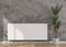 White heating radiator on grey concrete wall in modern room. Central heating system. Free, copy space for your text. 3D