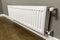 White heating radiator on wall in an apartment with wooden floor