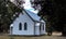 White historic vintage wooden rural country church surrounded by trees