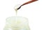 White honey pouring from wooden spoon in glass jar