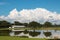 White horse barn on farm with lake and blue sky