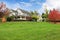 White horse farm American house during fall with green grass.