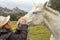 White horse in the green meadow receiving cuddles from his cowgirl with the white cowboy hat with many hugs and caresses and kisse