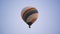 White hot air balloon with rainbow stripe floats in blue sky