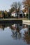 A white house and tall trees mirrored in the water