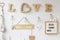 White house wall with arid wood decoration, with light bulbs, pictures, hearts and messages. Wooden love sign