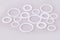 White hydraulic and pneumatic o-ring seals of different sizes scattered a white background.