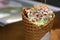 white ice cream in waffle cone with colored sprinkles and falling pieces of nuts