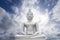 White image of Buddha with blue sky and cloud in background, light effect added ,filtered image,radial blurred sky,moving cloud
