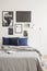 White industrial style floor lamp by a cozy bed with dark blue cushions in a bright hipster bedroom